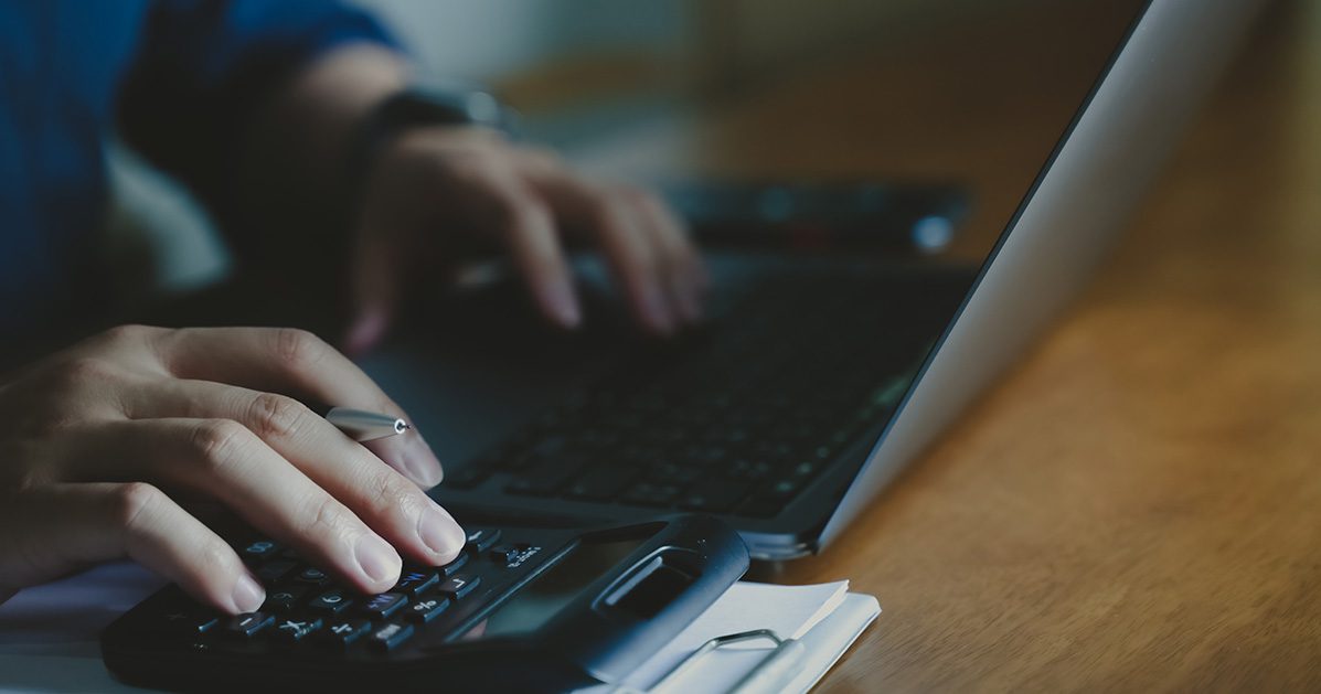 Man using a calculator and a computer.