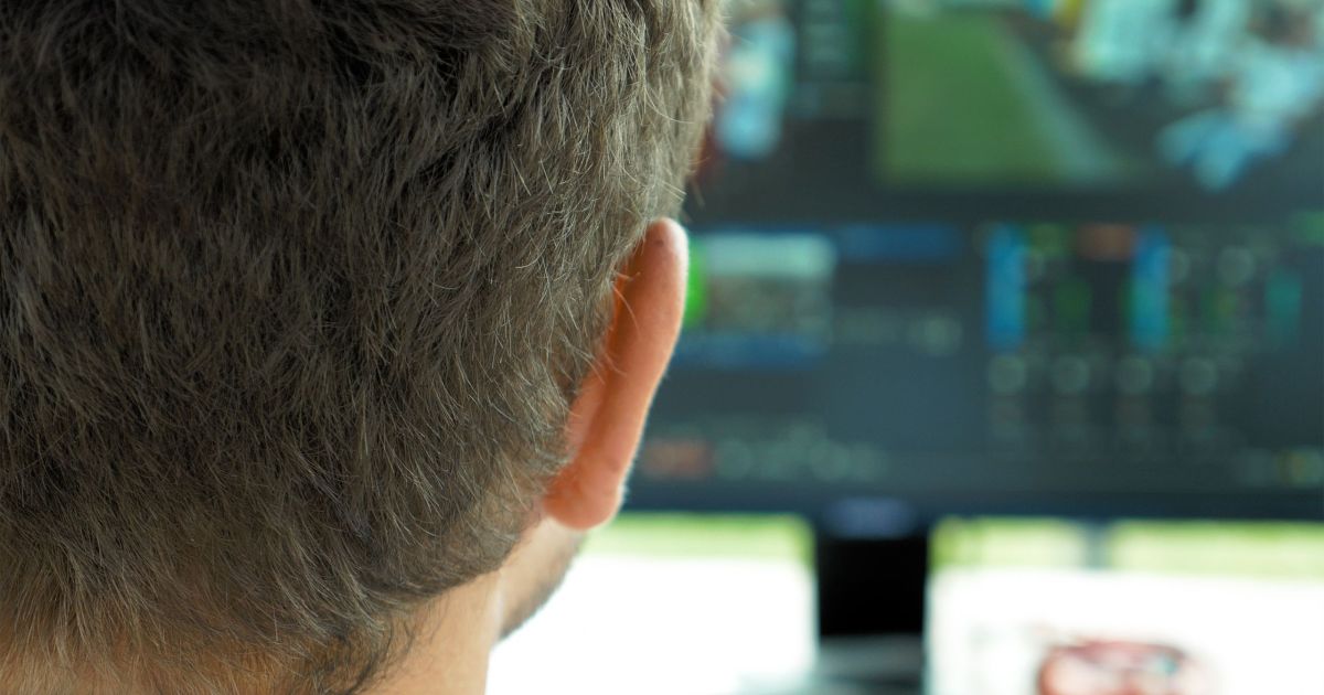 Video broadcast editor with headphones at screen