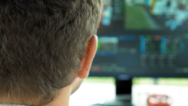 Video broadcast editor with headphones at screen