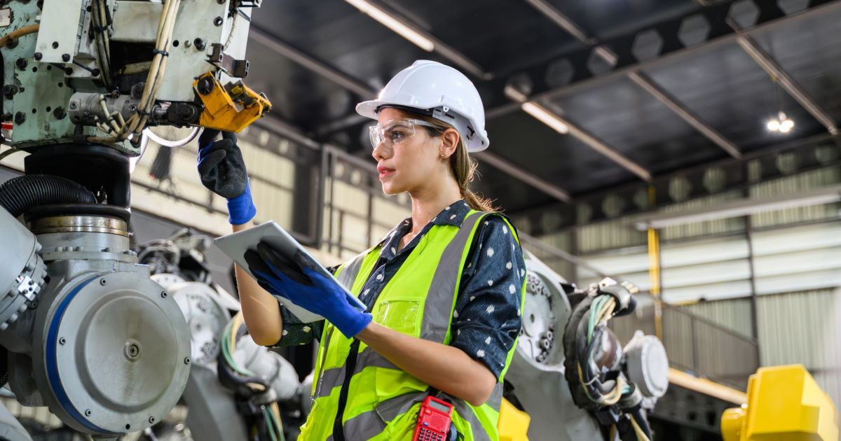 Woman manufacturing engineer with an ipad working on a machine.