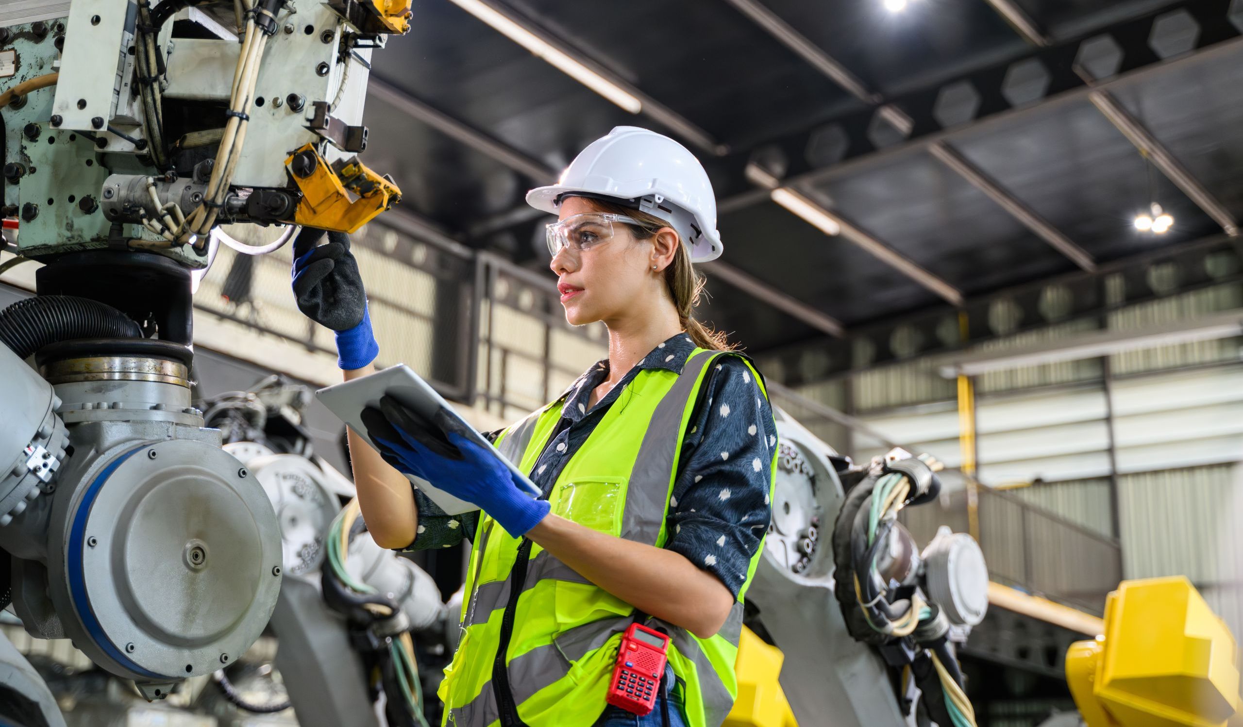 Woman manufacturing engineer with an ipad working on a machine.