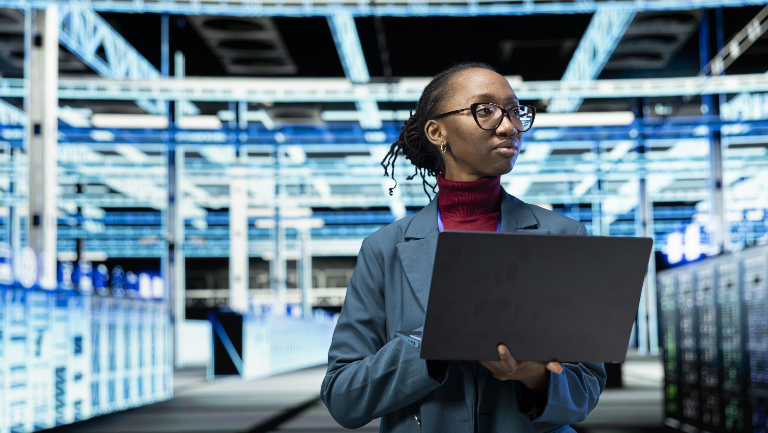 Data center female technician uses laptop program in data center