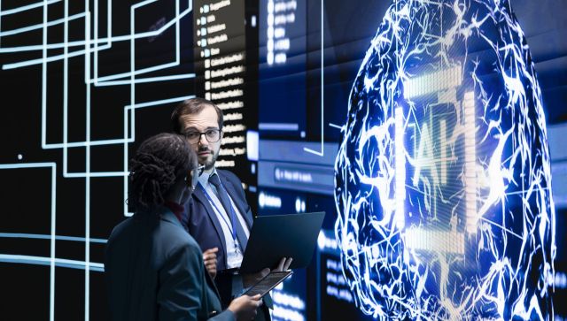 Engineering team observing rapid development of AI technology in RD lab, doing brainstorming. Teamworking colleagues monitoring progress of artificial intelligence architecture evolution, discussing