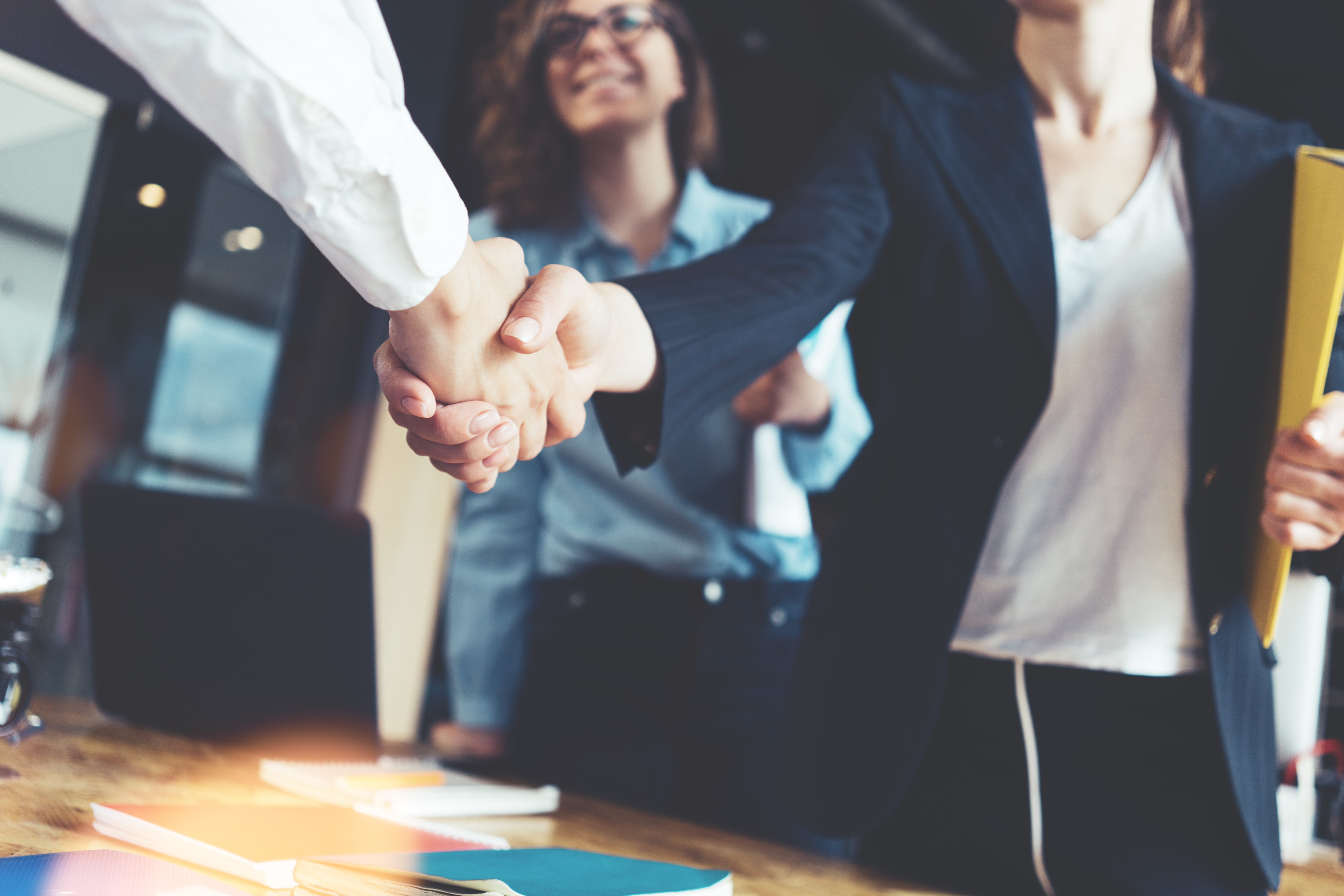 Young business people shaking hands in the office Finishing successful meeting Three persons