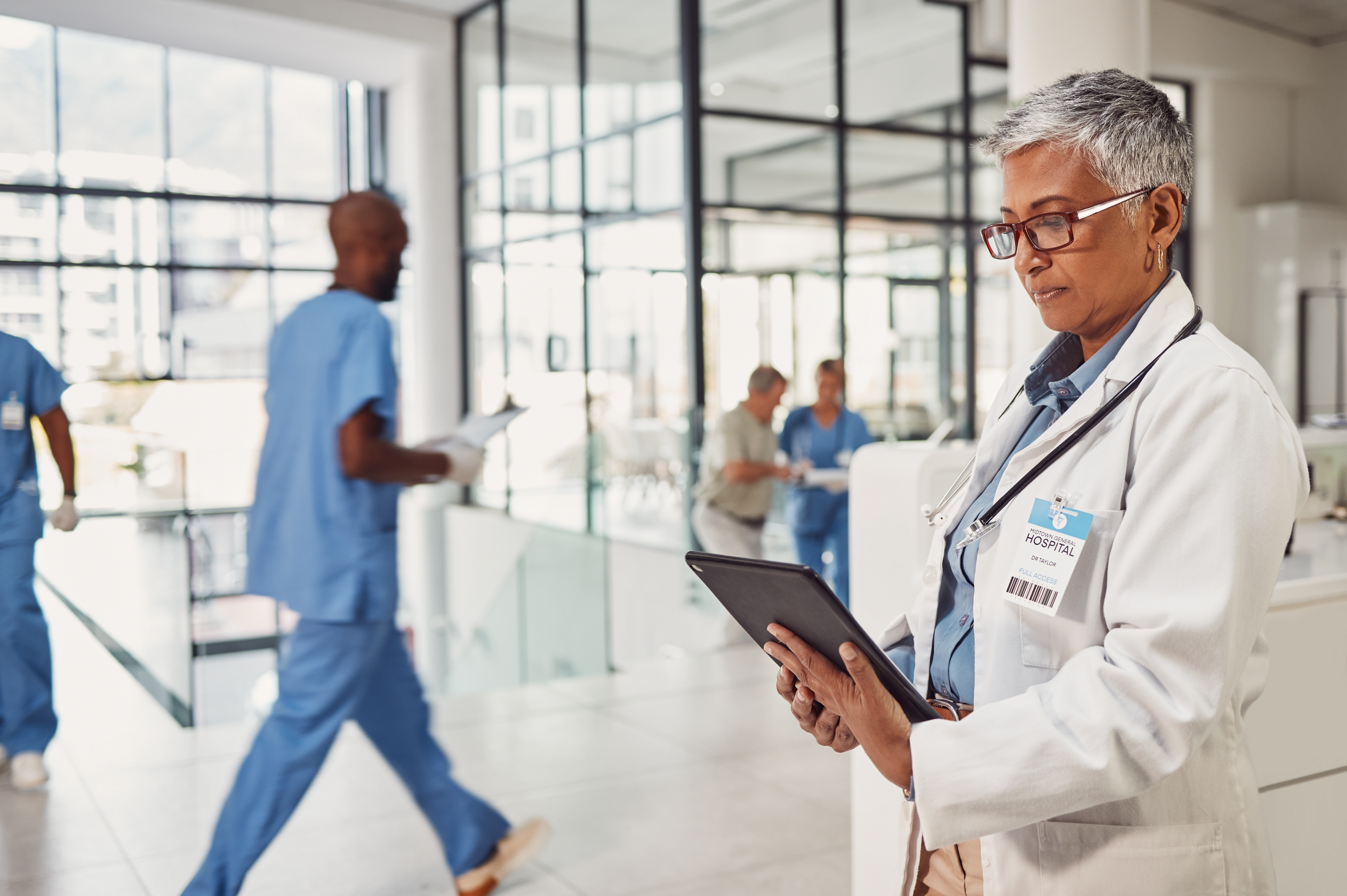 Doctor tablet and hospital or clinic lobby reading patient chart email or insurance information in India Internet medicine and technology medical worker checking online info schedule or report