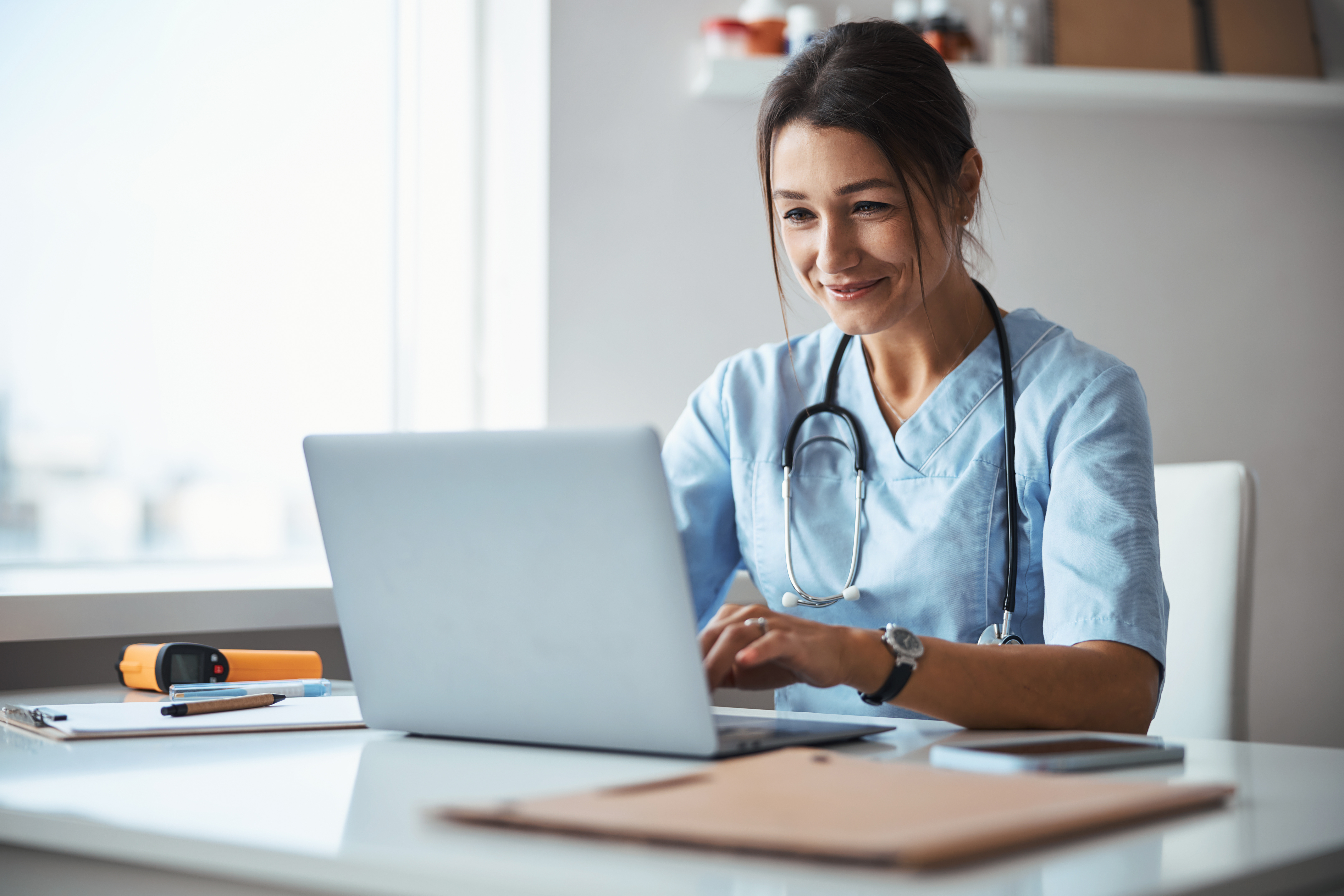 Joyful female doctor using notebook in clinic